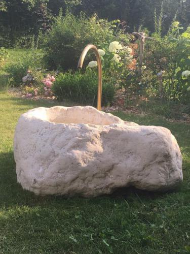 Fontaine bloc erratique en calcaire avec goulot en laiton sortant de la terre