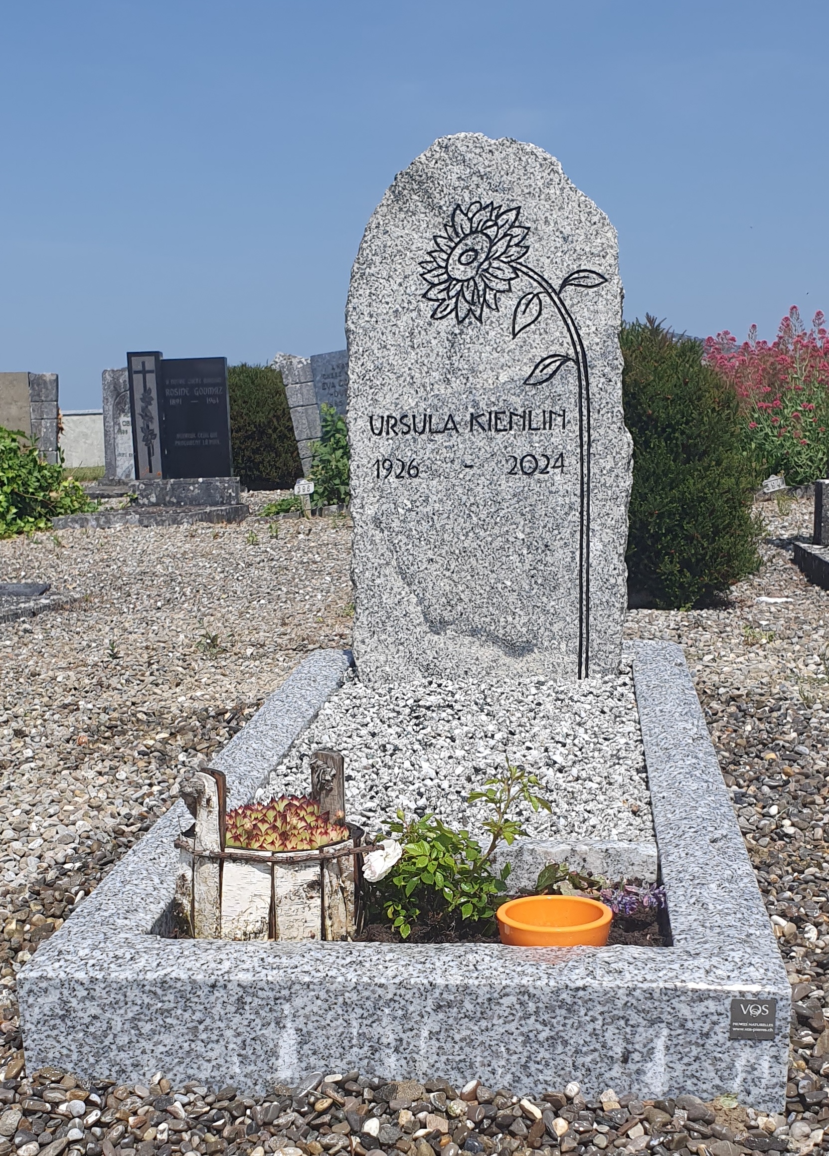 Monument funéraire en granit gris avec motif et texte gravé